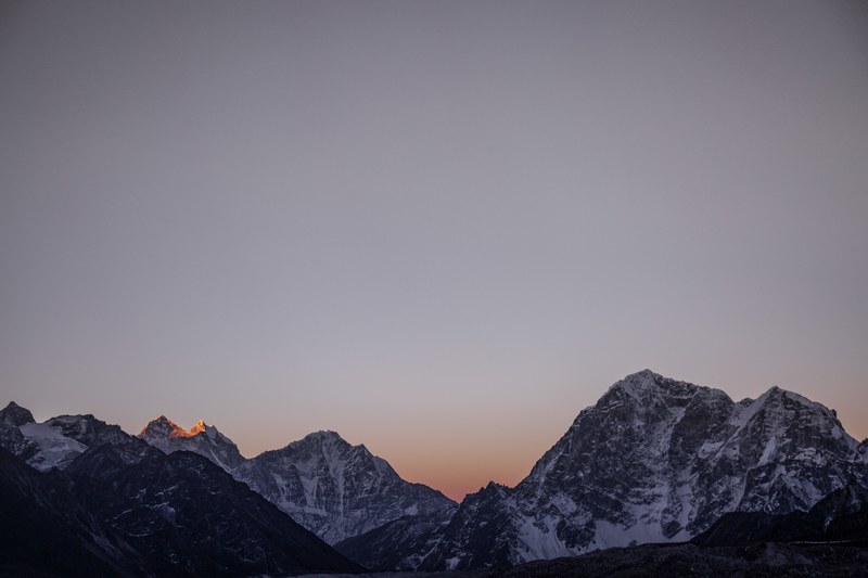 tall himalayan mountains with sharp peaks against a pale gray sky, rising sun 4k