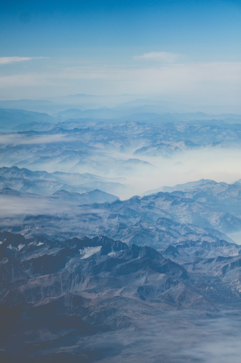 rugged mountain ridges covered in blue clouds and fog, adventures awaits 4k