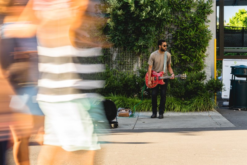 a street musician plays guitar on the sidewalk aside an open guitar case in seattle, be the music 4k