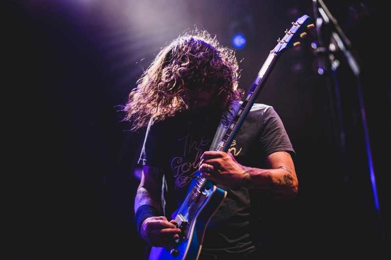 a long haired man in a t shirt playing an electric guitar on stage, red fang 4k
