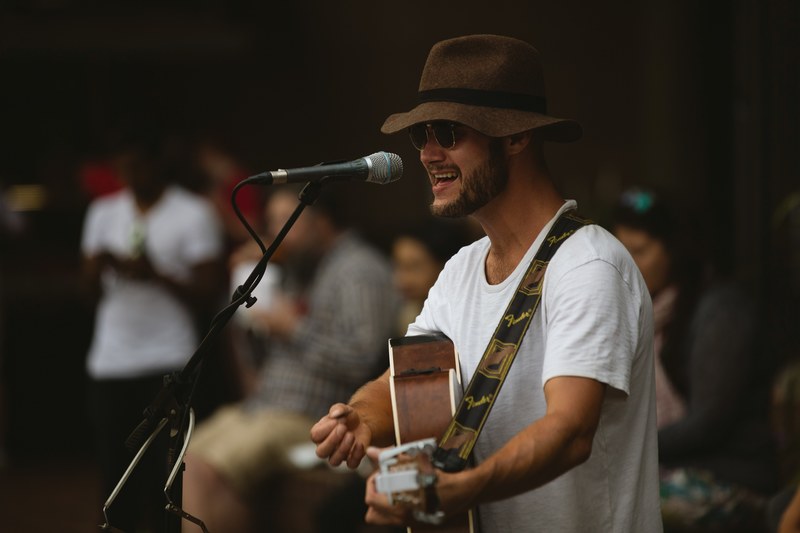 singer songwriter sings and plays guitar onstage at a show, street musician 4k