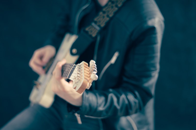 a blurry shot of a person in a leather jacket playing the guitar, guitarist in a leather jacket 4k