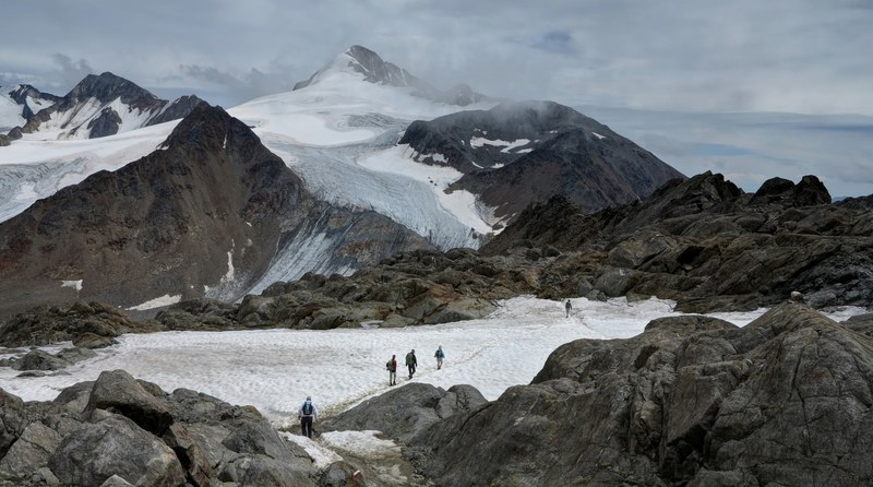 hikers walk a path through a snowy mountain landscape, hiking in the alps 4k