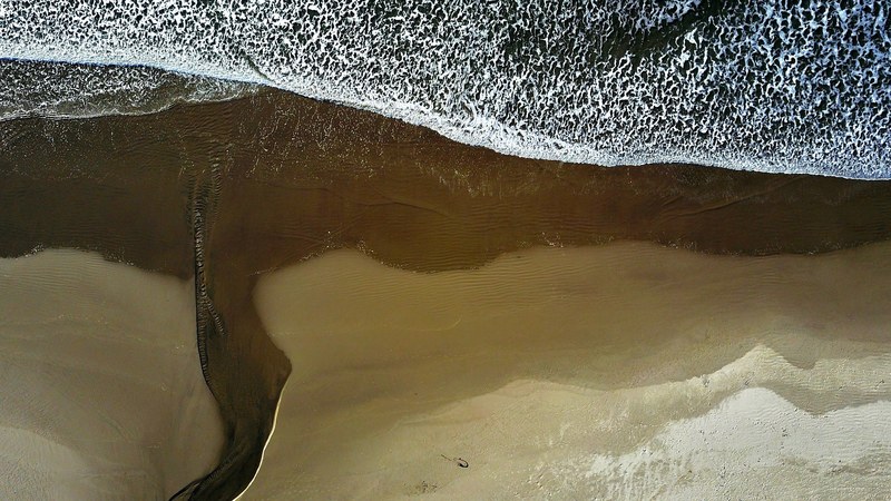 drone view of the ocean washing on the sand beach shoreline at arch cape oregon united states, over the ocean 4k