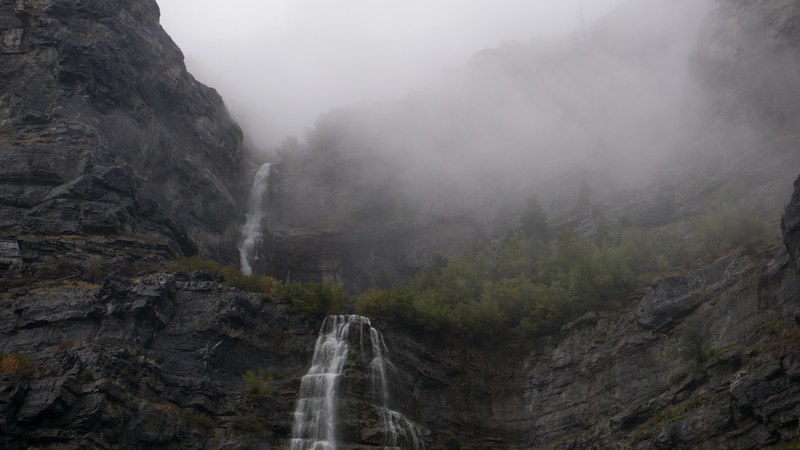 two waterfalls cascading down a rock face on a foggy day, two waterfalls in mist 4k