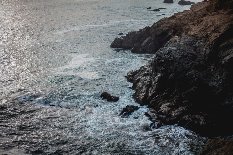 a rough sea below a jagged rocky coast, rocky coastline 4k