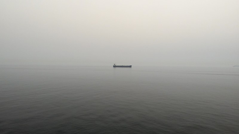 boat alone on calm gray waters on an overcast foggy morning, alone on the ocean 4k