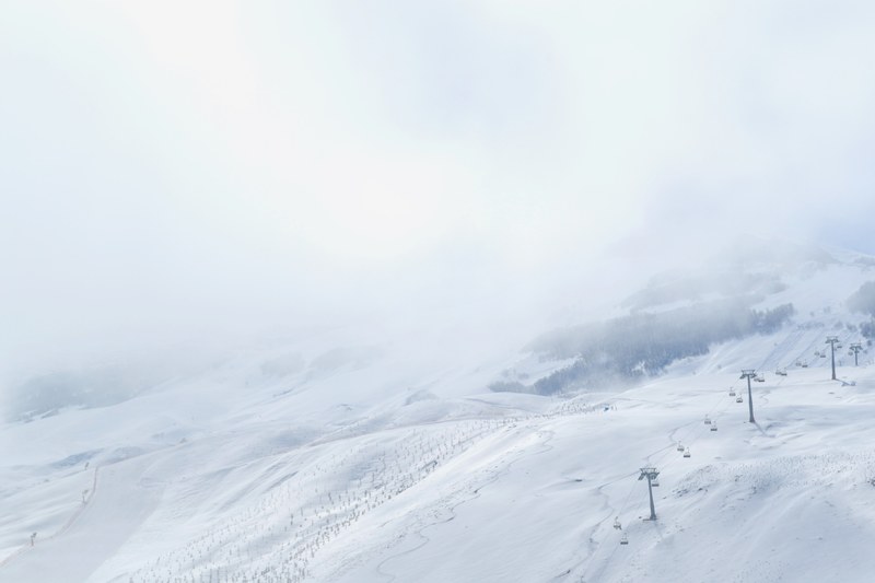 snow covered and foggy mountain side with ski trails and a chairlift in shahdag mountain resort, chairlift on foggy mountain 4k