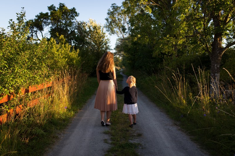 child and mother walk through park trail as shadows lengthen, together down the trail 4k