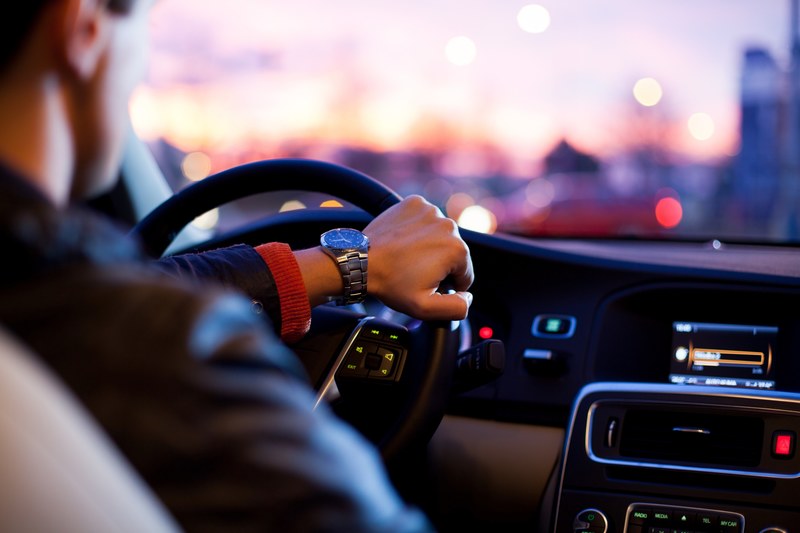 close up of a man with watch driving a car hand on steering wheel dashboard lights, hand on steering wheel 4k