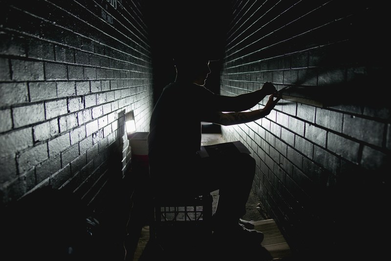 a man works in a dark corridor measuring bricks in adelaide, man in dark hallway 4k