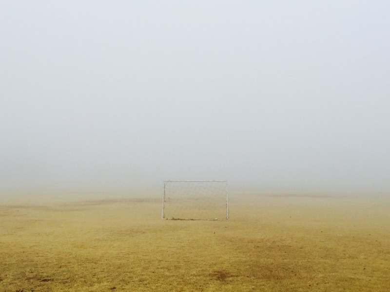 small soccer goal sitting on the yellow scorched grass field on a foggy day, small soccer goal on a foggy field 4k