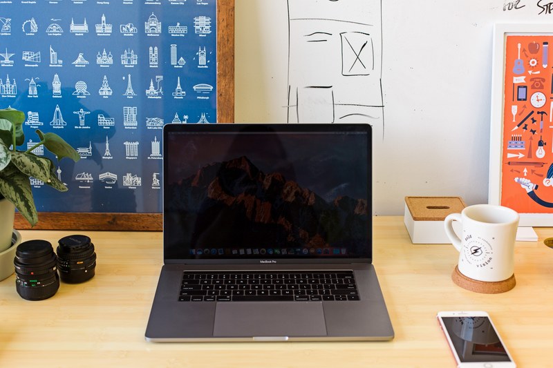a macbook and an iphone on a busy desk with design themed posters, designers desk mock 4k