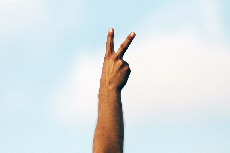 a hand with two fingers raised in a peace sign, proclaim peace 4k