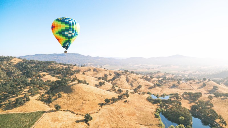 a colorful hot air balloon over golden hills in napa valley, hot air balloon over hills 4k