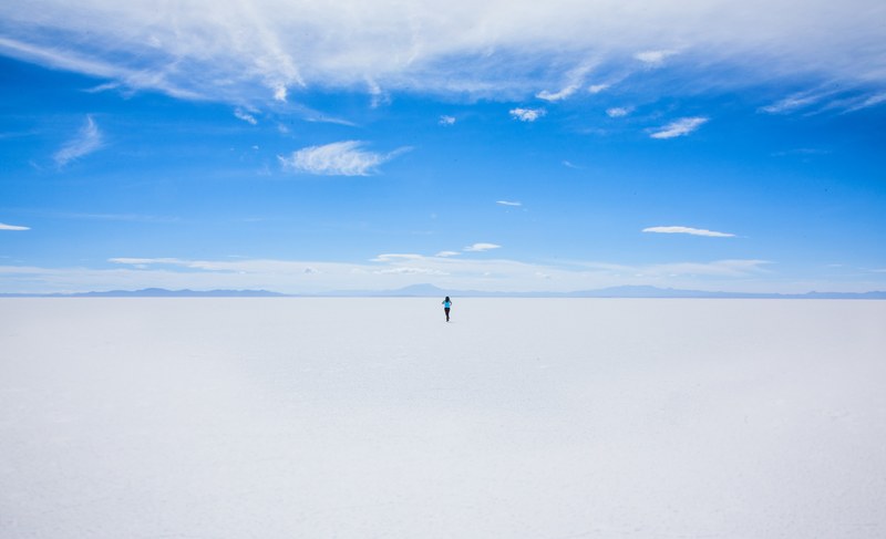 hiker walks alone toward the desert horizon in uyuni salt flat, solo adventures in the desert 4k