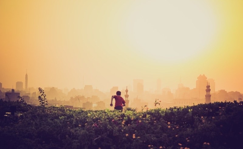 a kid running through a field with a sunrise as the backdrop, boy running in field 4k