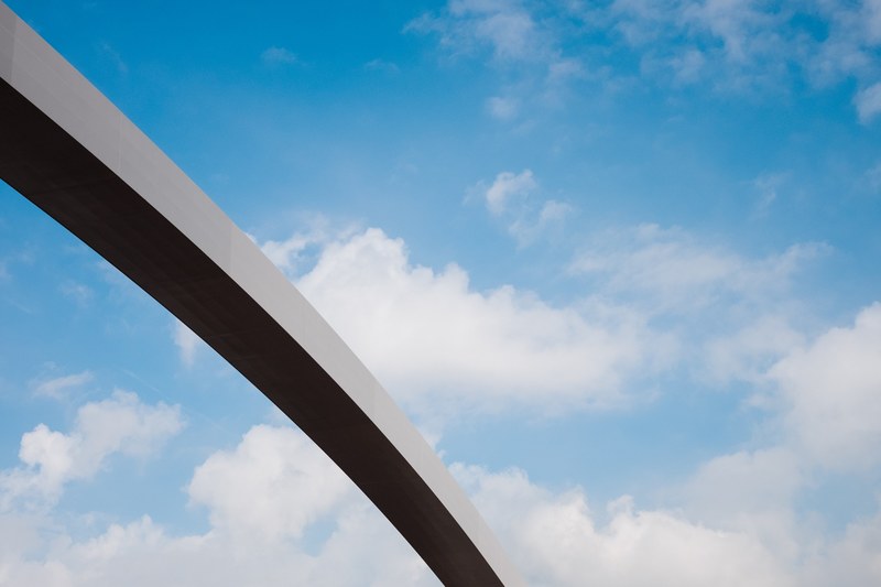 a section of a long concrete arch against a blue sky with fluffy clouds, long arch and fluffy clouds 4k