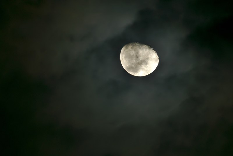 a bright moon in the night sky surrounded by wispy clouds, lunar in dark night 4k