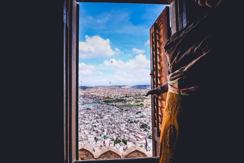 view of city from window with brown wooden shutter and cloudy blue sky nahargarh fort, window with a view 4k