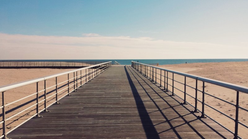 wide wooden boardwalk over the sandy beach towards the ocean, wide boardwalk 4k
