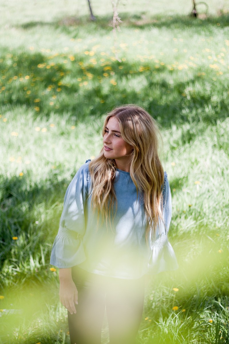 happy woman standing alone in a field and smiling, belle by me 4k