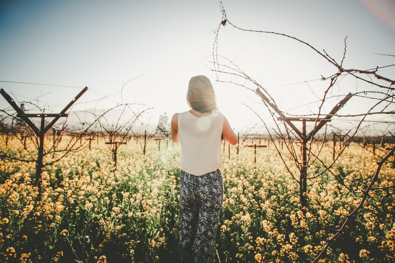 a dark haired woman strolling through an orchard full of white flowered plants, white plants in an orchard 4k