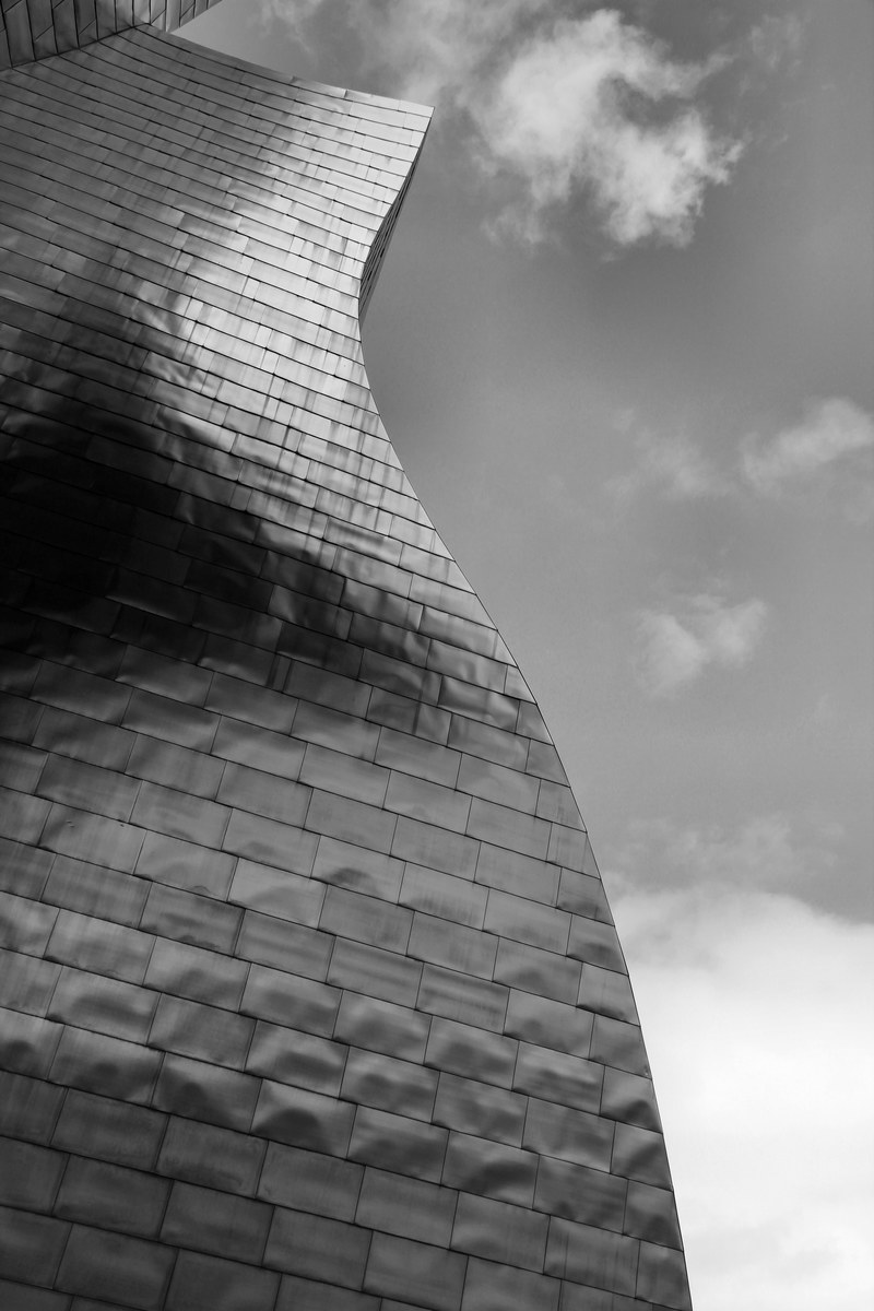 black and white shot of modern curved skyscraper building architecture in bilbao, curved bilbao skyscraper 4k