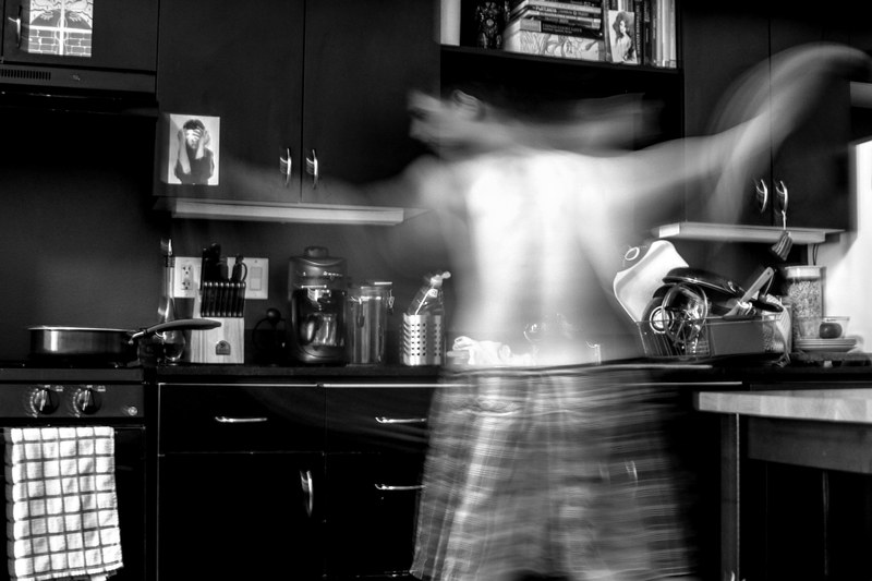 black and white blurred motion shot of topless man in pyjama bottoms moving energetically in kitchen, man in kitchen in motion 4k