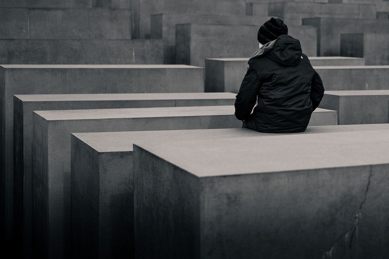 a man in jacket sits on a concrete block among the rows of concrete structures, _up alone 4k