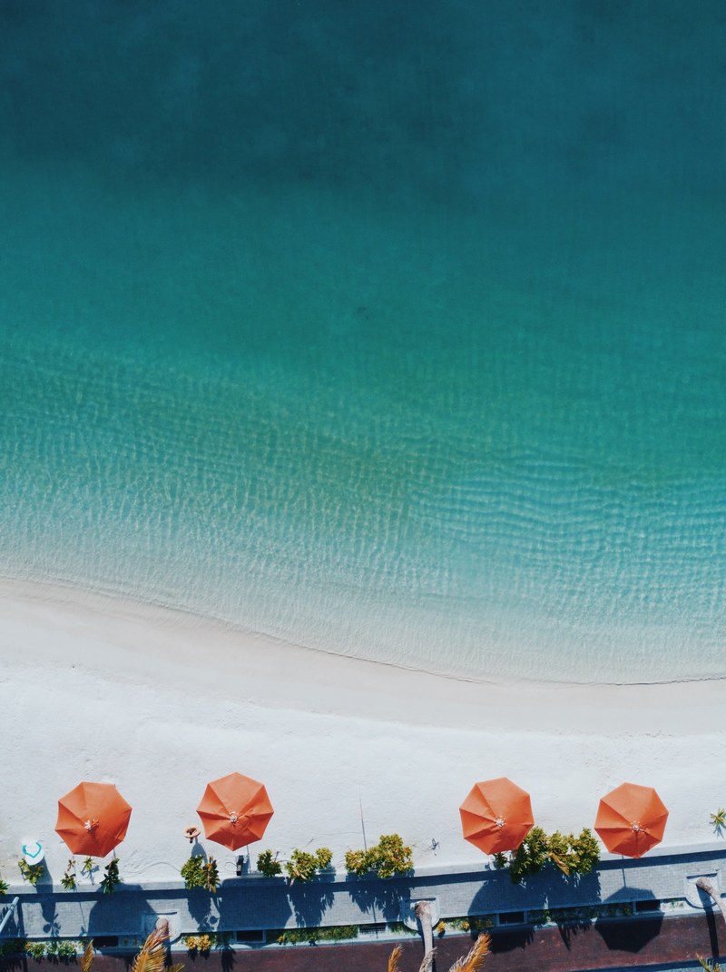 drone aerial view of the ocean washing on the sand beach with sun umbrellas and a footpath in rasfannu, a dream that cannot breathe_ 4k