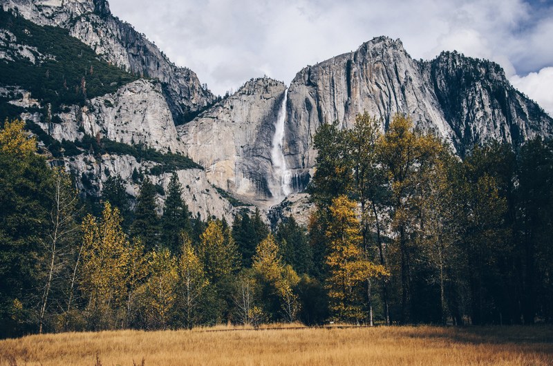 tall granite summits overlooking a golden field, waterfall in yosemite 4k