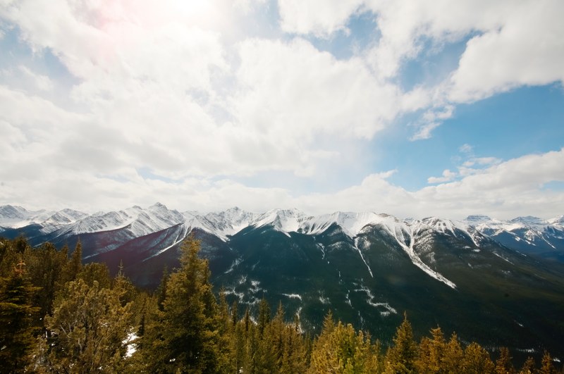 snowy mountain landscape with trees in the foreground and expansive clouds in banff, snowy mountain view in banff 4k