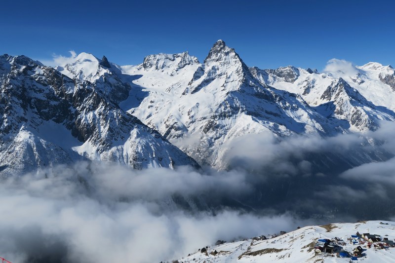 the summit of a mountain covered in snow clouds pass below the peak, mountain summit 4k