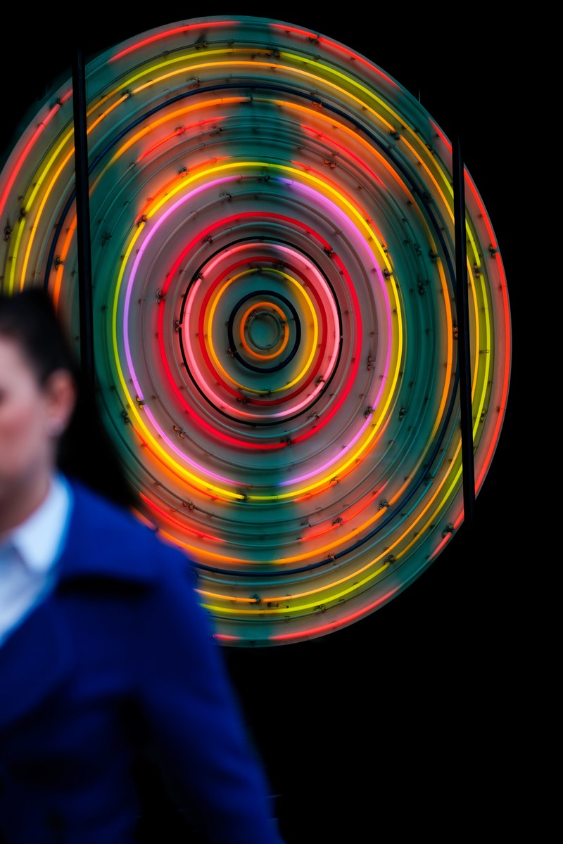 woman walking past a bright and colorful neon sign in london, neon sign in london 4k