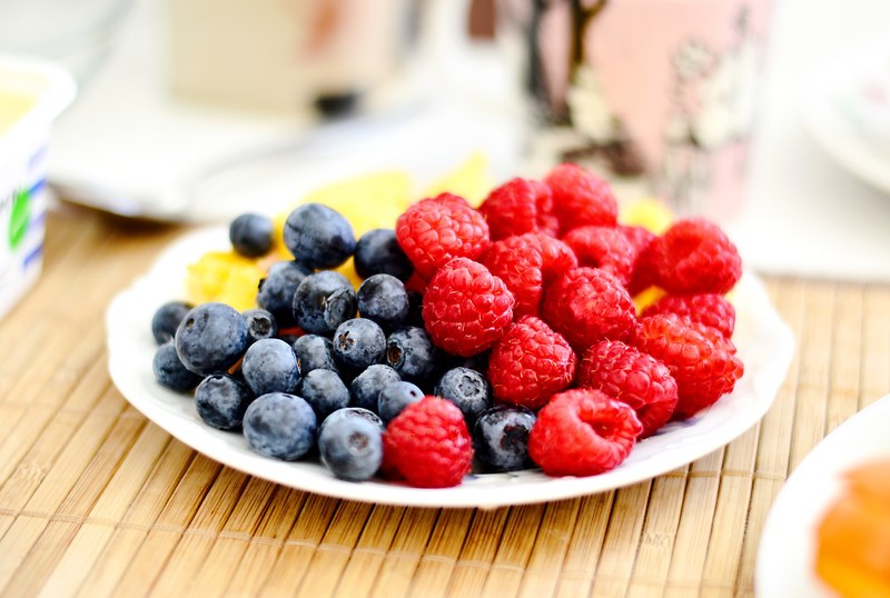 plate of fresh fruit with raspberries and blueberries on a picnic table, fruit platter 4k
