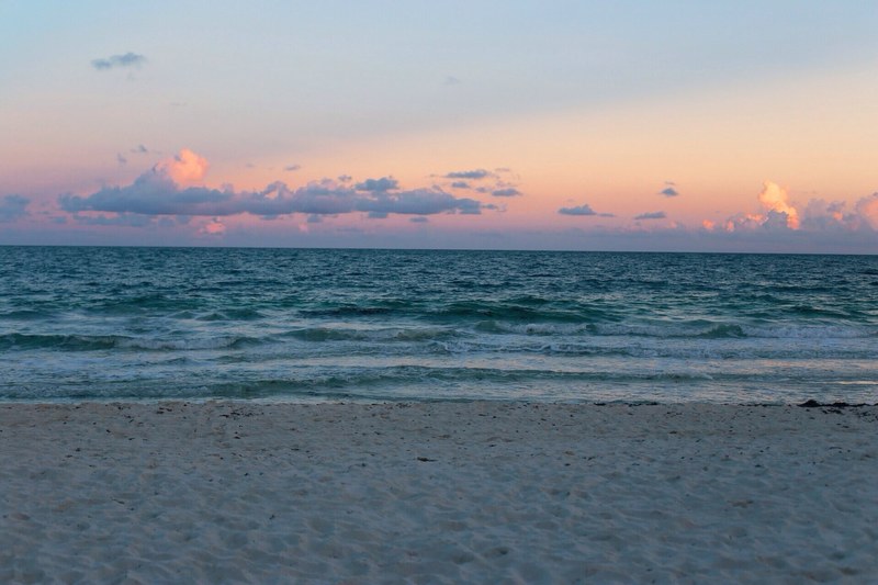 horizon with the sparse clouds above a tranquil ocean washed ashore in the sand on beach, tranquil ocean on beach 4k