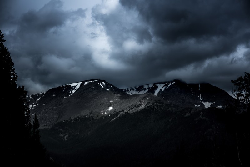 a dark cloudy overcast on snow covered mountain tops, _cloudy snow covered mountain peaks 4k
