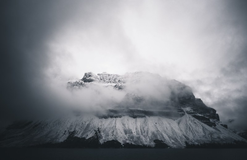 an ominous shot of a tall mountain shrouded in thick clouds in banff, cloud shrouded mountain in banff 4k