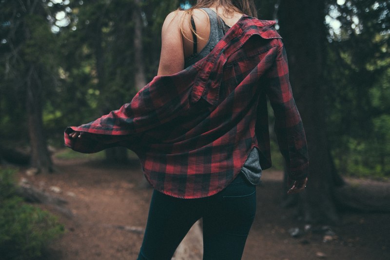 a woman taking off her flannel shirt in a forest, woman in a shirt in a forest 4k