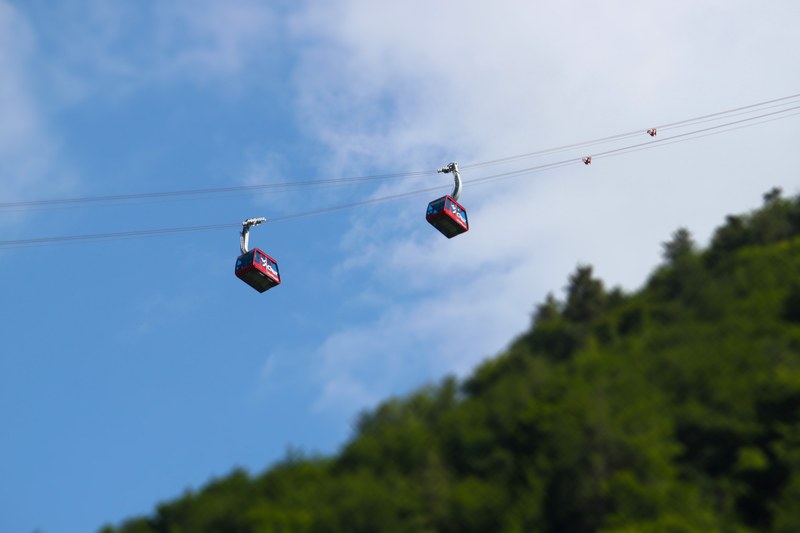 tilt shift view of cable cars ascneing up a mountain with clear blue skies in the background, _tilt shift cable car 4k