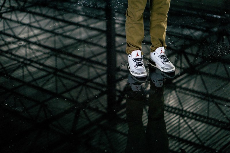 a reflection in the puddle of water of a man wearing air jordan sneakers, _air jordan sneakers reflection 4k