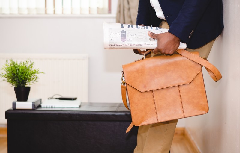 a businessman in a navy blue jacket with a business newspaper and a leather suitcase, businessman with a suitcase 4k