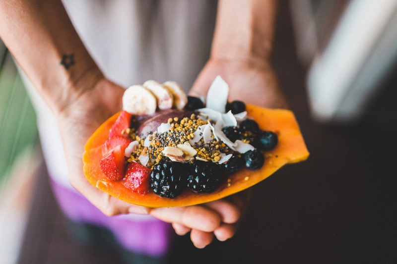 person with star tattoo holding out a healthy snack with various berries and juicy fruits, healthy tropical breakfast 4k