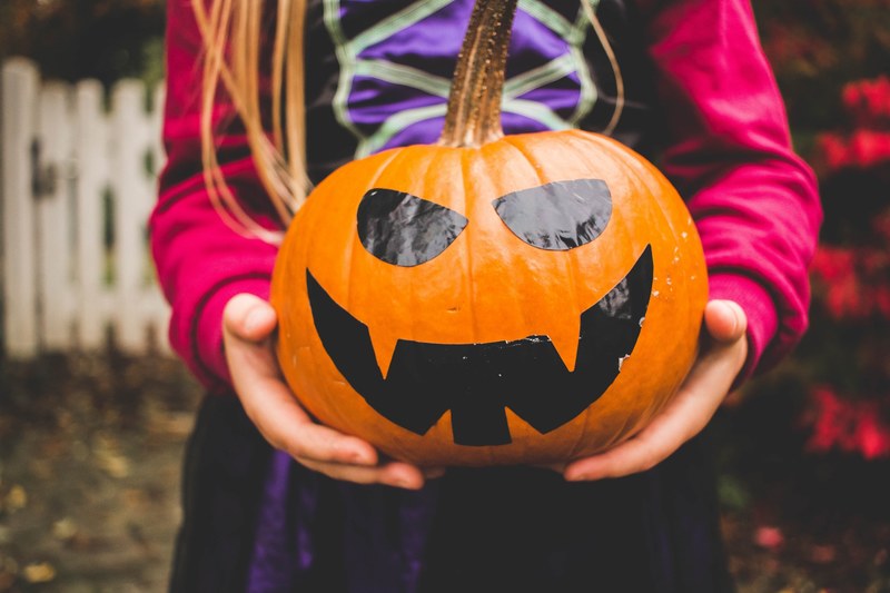 macro view of a child dressed in a costume holding a jack o lantern for halloween in germany, _child holding jack o lantern 4k