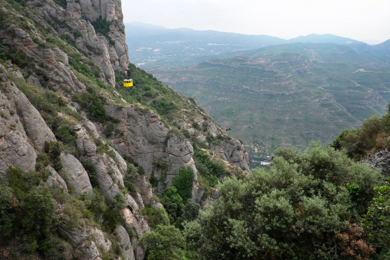 long shot of yellow cable car travelling through mountain valley with vegetation, yellow cable car travelling through valley 4k
