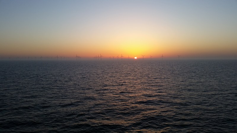 view of the sea during sunset and wind turbines visible at the horizon, windmills on the horizon 4k