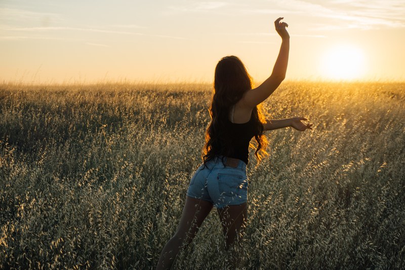 happy woman dancing in a field of grass at sunset, dancing in the sun 4k