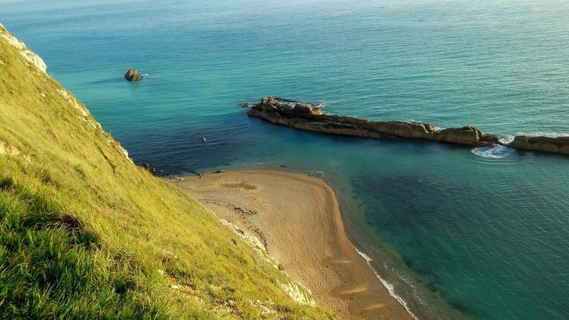 sandy beach shoreline viewed from grass mountain at durdle door, sand beach shoreline 4k