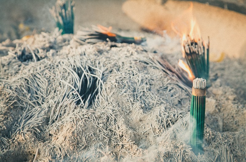 a pit of incense burning next to a heap of ash, burning incense pit 4k